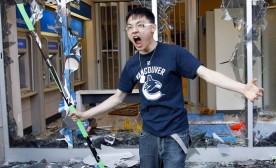 A Canucks fan holds a hockey stick after smashing the windows of a bank as he reacts to the Canucks losing the NHL Stanley Cup to the Bruins in Vancouver