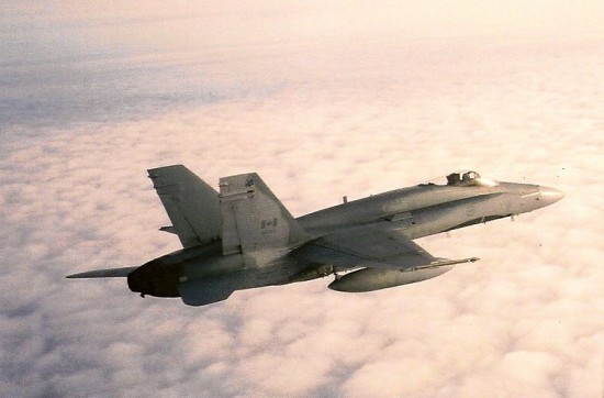 Lone CF-18 skims the cloud layer, flying into the sunset