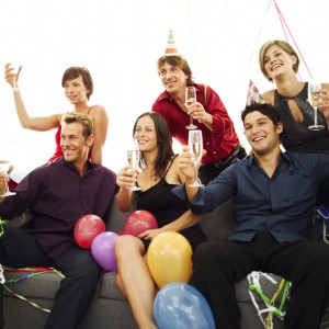 Group of Young People at a Party Sitting on a Couch with Champagne