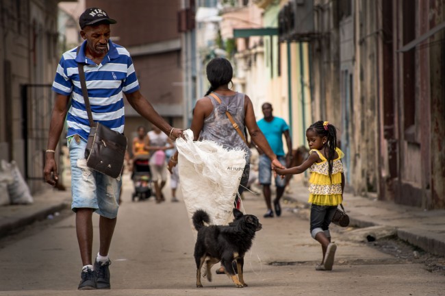 While crossing paths on the streets of Havana, a little girl and dog share a moment